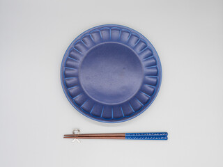 白い背景に置かれた紺色のお皿とお箸