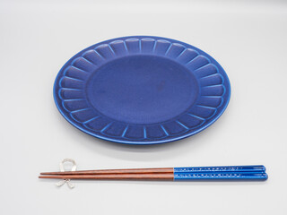 白い背景に置かれた紺色のお皿とお箸