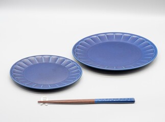 白い背景に置かれた紺色の2枚のお皿とお箸