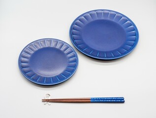 白い背景に置かれた紺色の2枚のお皿とお箸