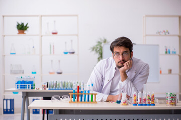 Young male chemist in drugs synthesis concept