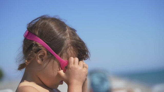 Child wears swimming glasses in summer by the sea. Little girl wearing goggles and diving in swimming pool 