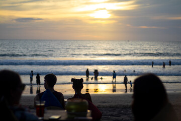 INDONESIA - January 10, 2022: crowd of tourists enjoy the sunset at a bar on Batu Belig beach, Bali.