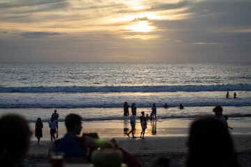 INDONESIA - January 10, 2022: crowd of tourists enjoy the sunset at a bar on Batu Belig beach, Bali.
