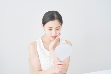 鏡を見る女性　肌トラブル