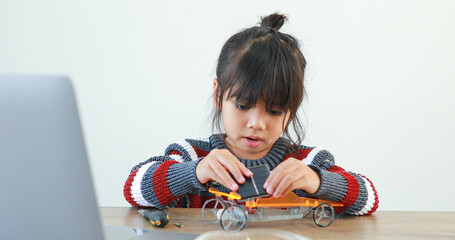 The little girl asian building robotic car in science lesson in the house . Which increases the development and enhances learning skills gifted brilliant children working with technology.