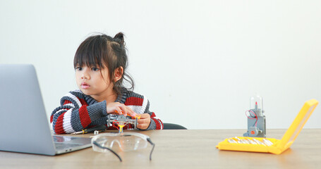 The little girl asian building robotic car in science lesson in the house . Which increases the development and enhances learning skills gifted brilliant children working with technology.