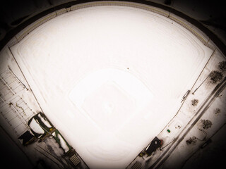 A vintage feel look of an aerial view of a snow covered baseball field in winter