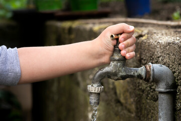 Hand from a child is turning tap water valve