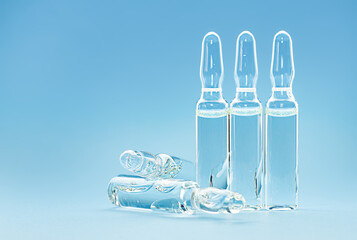 five transparent ampoules with medicine on a blue background