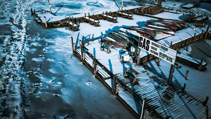 Frozen pier on snow covered river at closed seasonal resort 