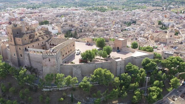Aerial view of fortified castle and Basilica of Vera Cruz on hill dominating residential areas of Spanish town of Caravaca de la Cruz on summer day. High quality 4k footage