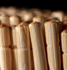 Close up of wooden toothpicks on a black background.