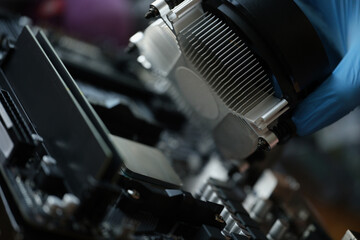 A hand in a glove installs a new cooler for a pc