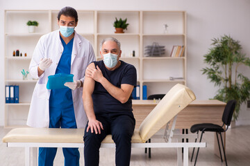 Obraz premium Old man visiting young doctor in covid-19 vaccination concept