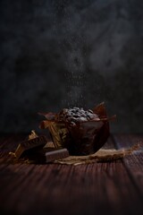 Obraz na płótnie Canvas Chocolate muffin with powdered sugar on top on a dark wooden background.
