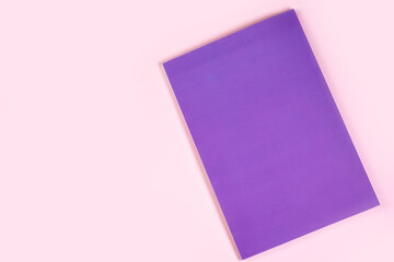 Notebook in the color Very peri trend 2022 lies on a pink table.