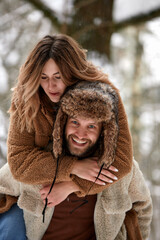 People, season, love and leisure concept - happy couple hugging and laughing outdoors in winter. Couple embracing and having fun in snowy winter park