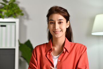 Portrait shot of happy friendly and confident Asian businesswoman making video call, looking at camera and talking, discussing strategy with partners online at home