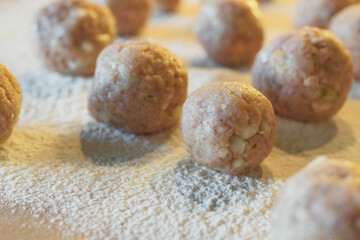 Uncooked meatballs close up on wooden board poured by flour. Swedish meatballs in a creamy white sauce recipe