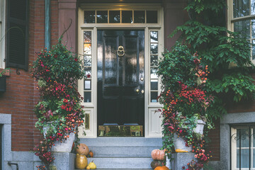 View of an entrance to apartment building. Stoop with plants, flowers and pumpkins for Thanksgiving...