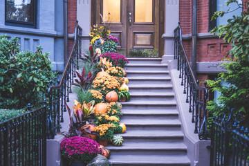 View of an entrance to apartment building. Stoop with plants, flowers and pumpkins for Thanksgiving...