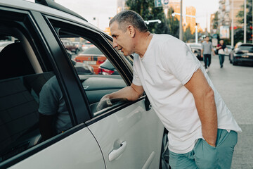 man looks into an open car window