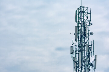 tall telecommunication tower or transmitter broadcasting the internet network and mobile data at the cloudy sky background