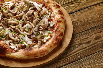 Delicious homemade pizza with mozzarella, mushrooms, beef and chicken. Wooden background, selective focus.