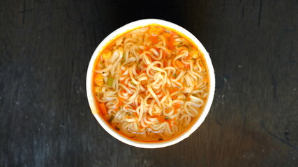 Instant noodles in package cup Asian meal isolated on dark background