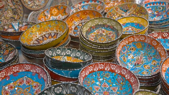 Rows of beautiful, ornamented be floral pattern, colorful ceramic plates on the market counter. Shot in motion. Closeup