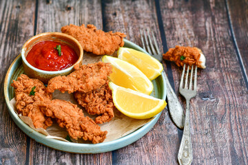
 Crispy  deep fried   chicken strips and wedges potato. Breaded  with cornflakes chicken  breast fillets  with chilly peppers and fresh   basil on wooden rustic background