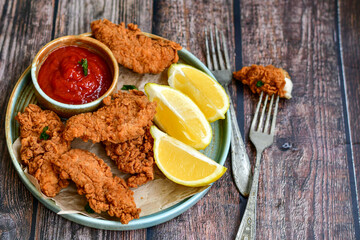 
 Crispy  deep fried   chicken strips and wedges potato. Breaded  with cornflakes chicken  breast fillets  with chilly peppers and fresh   basil on wooden rustic background
