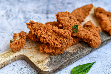 
 Crispy  deep fried   chicken strips and wedges potato. Breaded  with cornflakes chicken  breast fillets  with chilly peppers and fresh   basil on wooden rustic background