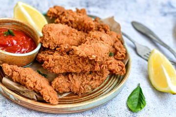 
 Crispy  deep fried   chicken strips and wedges potato. Breaded  with cornflakes chicken  breast fillets  with chilly peppers and fresh   basil on wooden rustic background