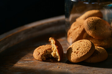 Food photography details. Close up view of some home made cookies next to a glass jar on a wooden table. Perfect for breakfast of with a coffee.