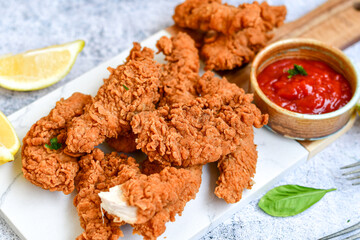 
 Crispy  deep fried   chicken strips and wedges potato. Breaded  with cornflakes chicken  breast fillets  with chilly peppers and fresh   basil on wooden rustic background