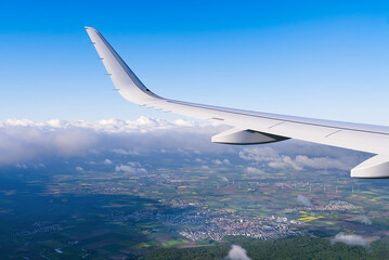 View of airplane white wing flying in blue sky over clouds. Travel concept