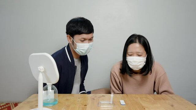 4K, Asian couple Sitting for COVID-19 test results, coronavirus epidemic prevention ideas Rapid antigen test kit to test yourself COVID-19 epidemic at home.