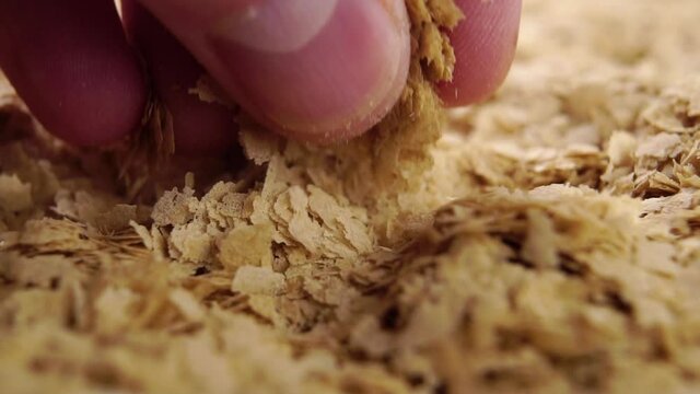 Hand takes a pinch of brewer's yeast flakes. Falling on a heap in slow motion. Natural supplement. Macro shot. Super food concept