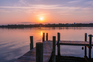 Obraz premium Pink sunrise over the Sebastian River over a wooden pier in Little Hollywood, Mikko, Florida. Typical view of beautiful nature in Florida
