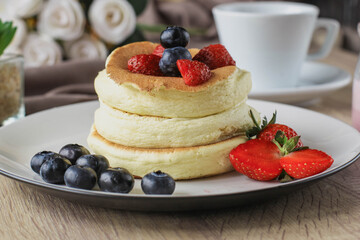 Close-up of Japanese specialties called souffle pancakes with berry on top served on a wooden table