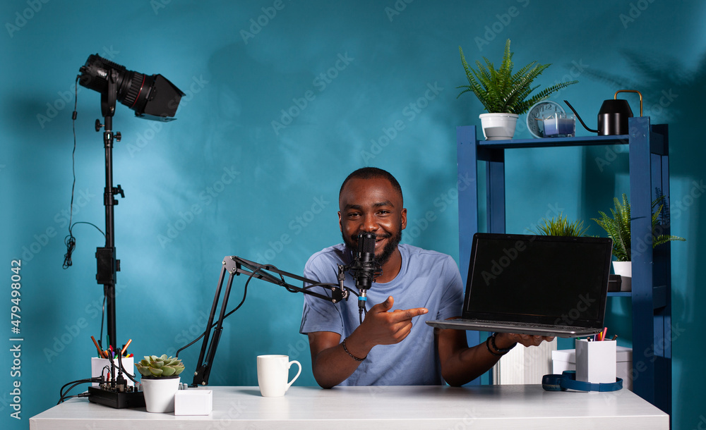 Poster african american vlogger doing review for new laptop model pointing out important features sitting a