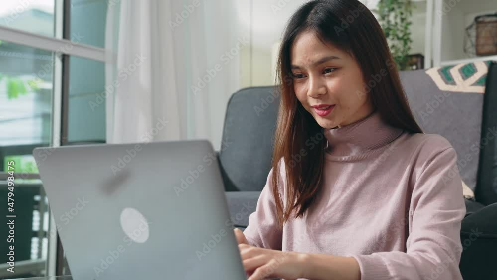 Poster young happy woman sit on the sofa in house and using laptop computer with type on a keyboard.
