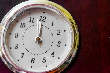 Vintage and classic metal clock on brown wood with a grainy effect