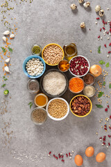 Fototapeta na wymiar Concept of vegetarian food and diet on gray concrete background, legumes, seeds and cereals in colored bowls grouped with copy space