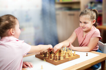 two girls playing chess at home