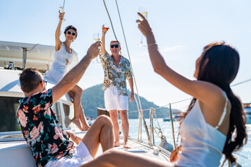 Group of Caucasian people friends enjoy luxury party drinking champagne together while catamaran...