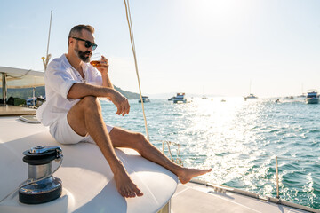 Caucasian man enjoy outdoor luxury lifestyle with alcoholic drinks while catamaran boat sailing at...