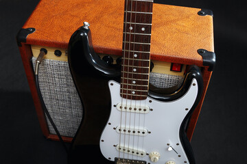 Fototapeta na wymiar Guitar combo amplifier with black guitar on black background.